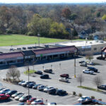 Linwood Square, Bank of America, Nail Trap, H&R Block, City Gear, USPS Post Office, Bee Beauty, and parking lot. Aerial view.