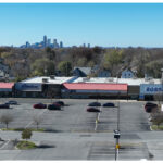 Linwood Square, Subway, Wing Stop, Rainbow, Ross Dress For Less, and parking lot. Aerial view, downtown Indianapolis skyline behind stores.